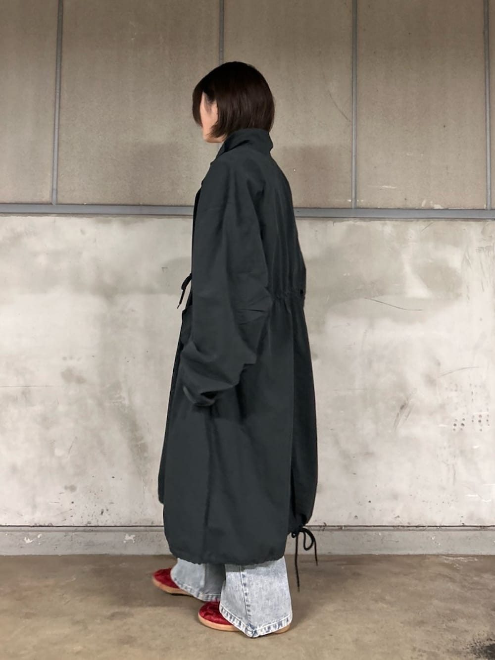 ブラック系のモッズコート、ブルー系のデニムパンツ、レッド系のカーディガン/ボレロを着用したレディースの春コーディネートの5枚目の写真