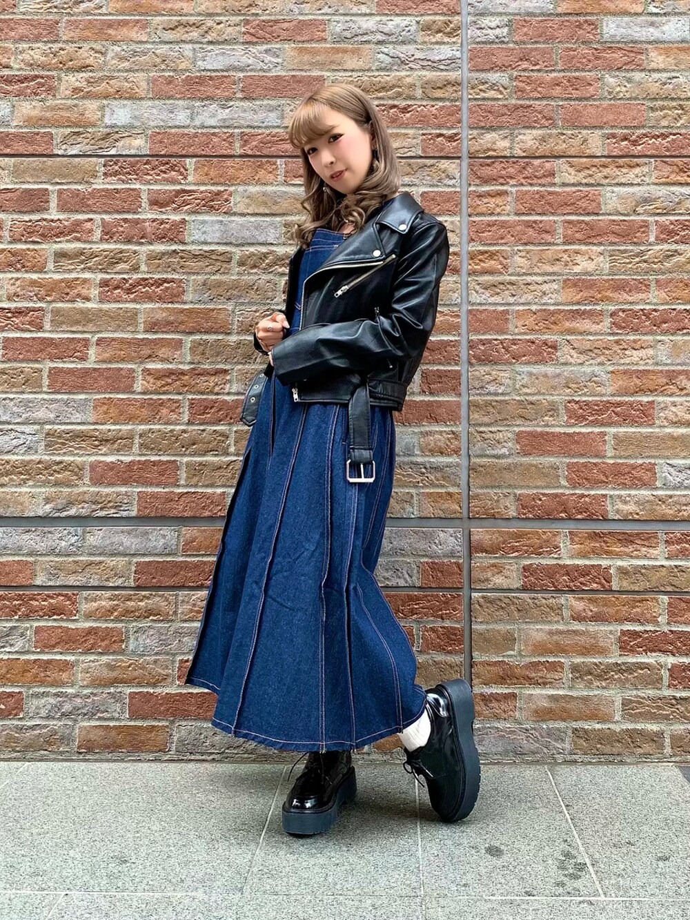 ブルー系のジャンパースカート、ブラック系のドレスシューズ、ブラウン系のTシャツ/カットソーを着用したレディースの秋コーディネートの2枚目の写真