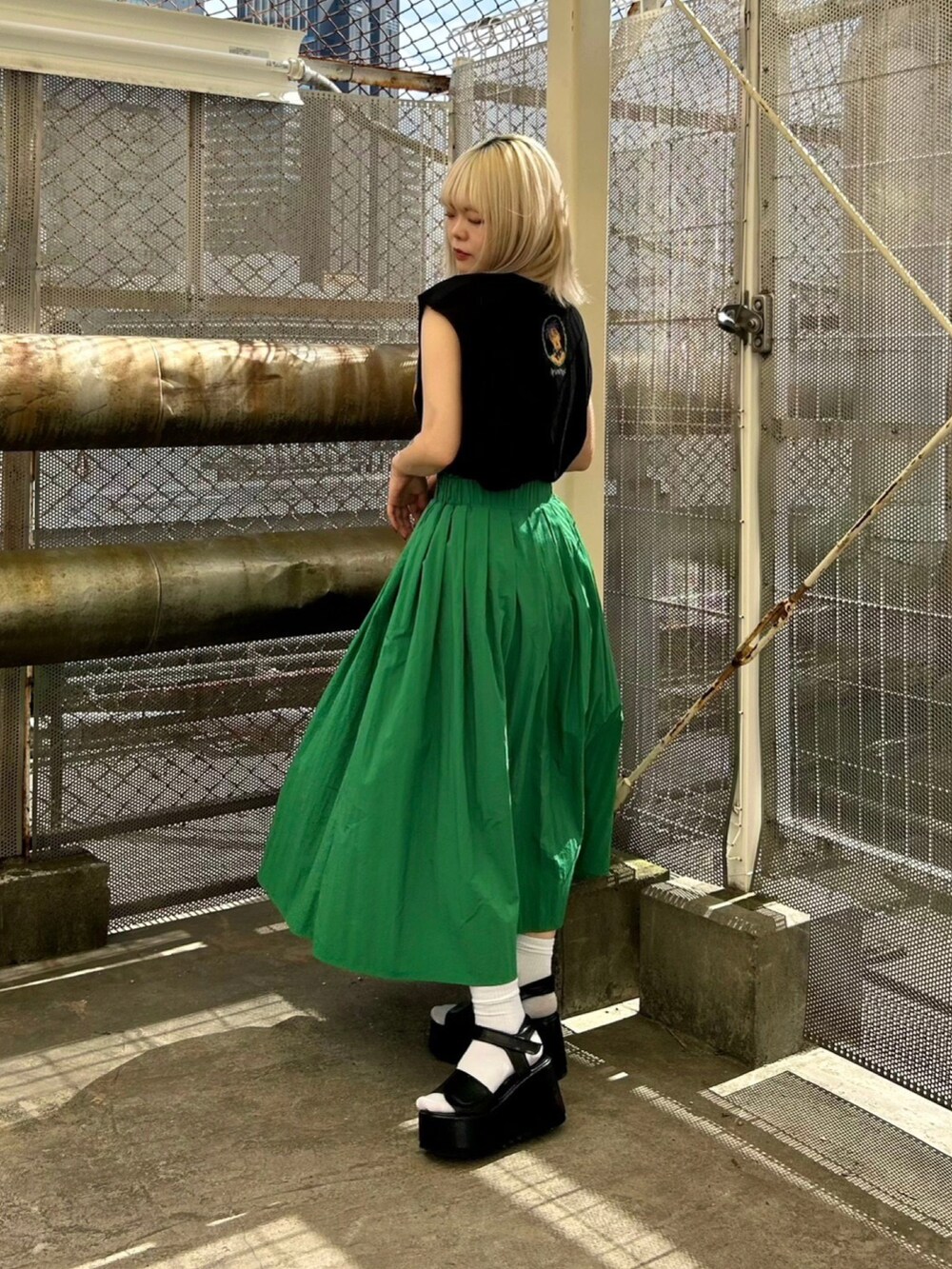 ブラック系のサンダル、ブラック系のTシャツ/カットソー、グリーン系のスカートを着用したレディースの夏コーディネートの2枚目の写真