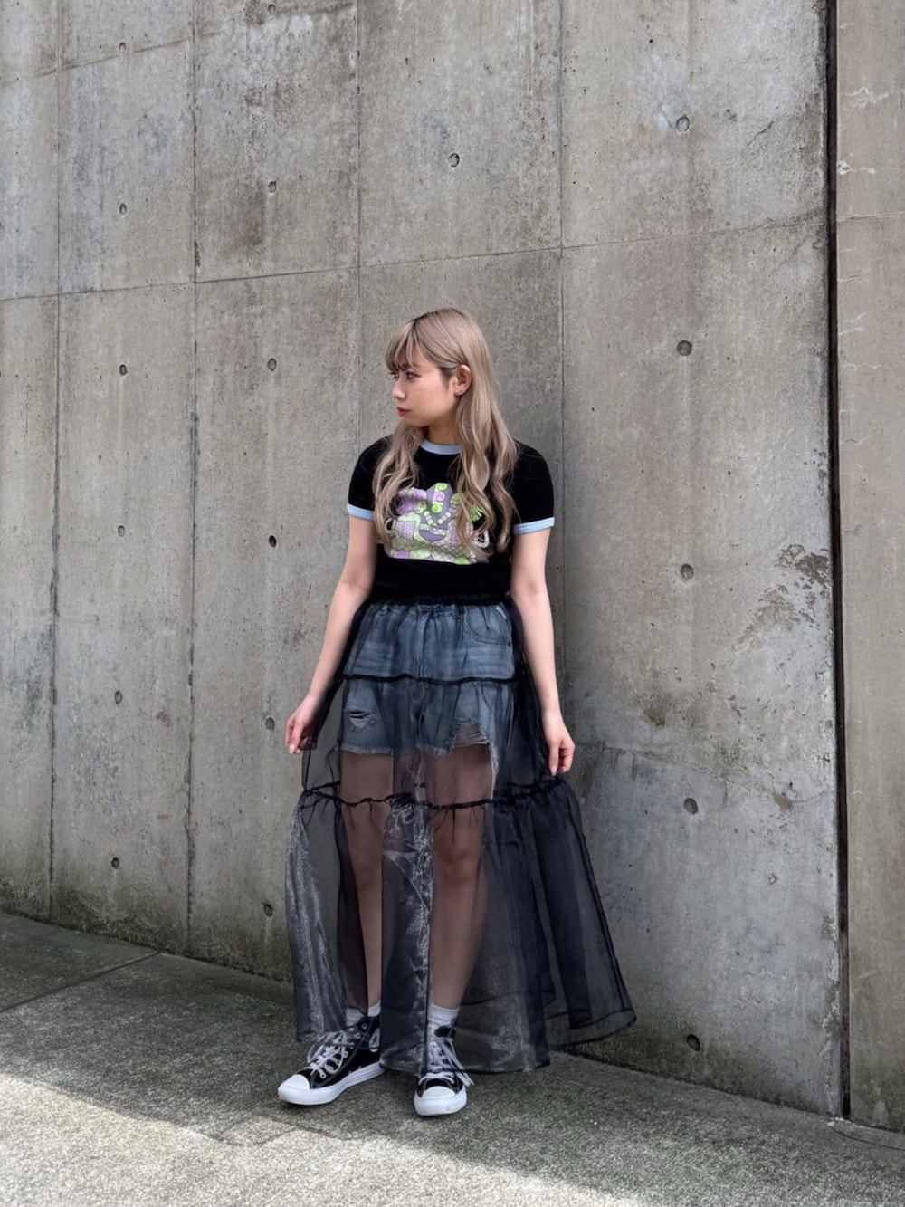 ブラック系のTシャツ/カットソー、ブルー系のデニムパンツ、ブラック系のスカートを着用したレディースの春コーディネートの3枚目の写真