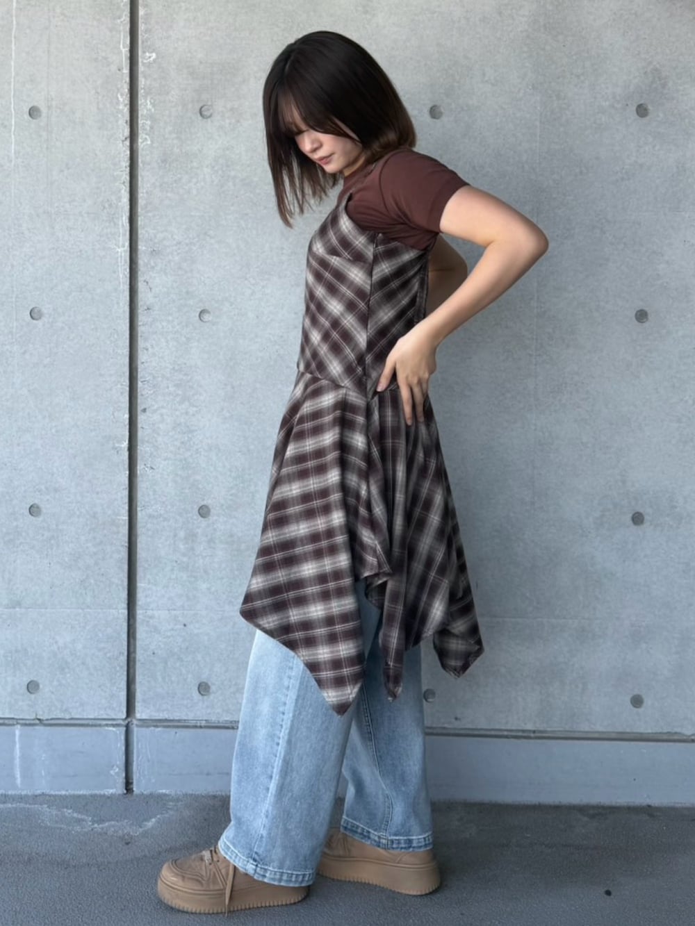 ブルー系のデニムパンツ、ブラウン系のワンピース、ブラウン系のニット/セーターを着用したレディースの春コーディネートの3枚目の写真