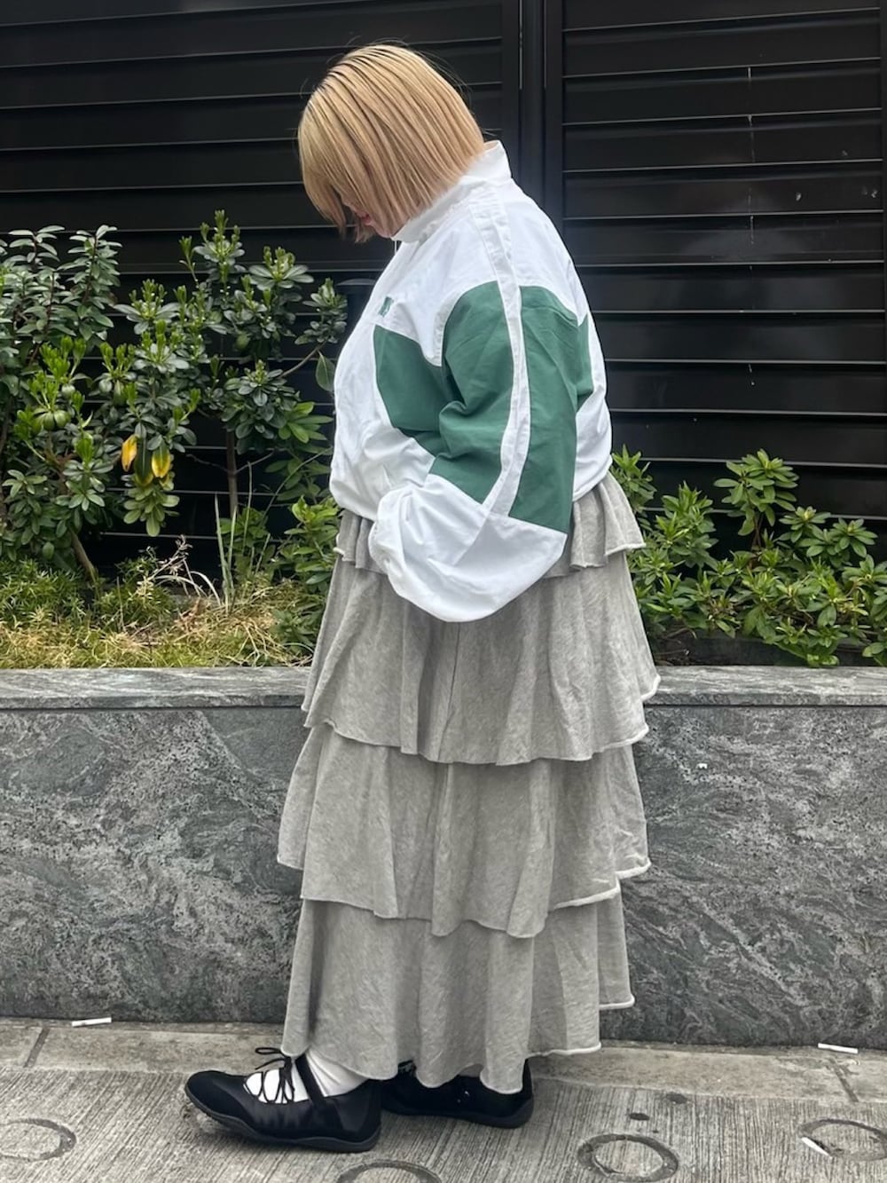 グレー系のスカート、ホワイト系のナイロンジャケットを着用したレディースの春コーディネートの3枚目の写真