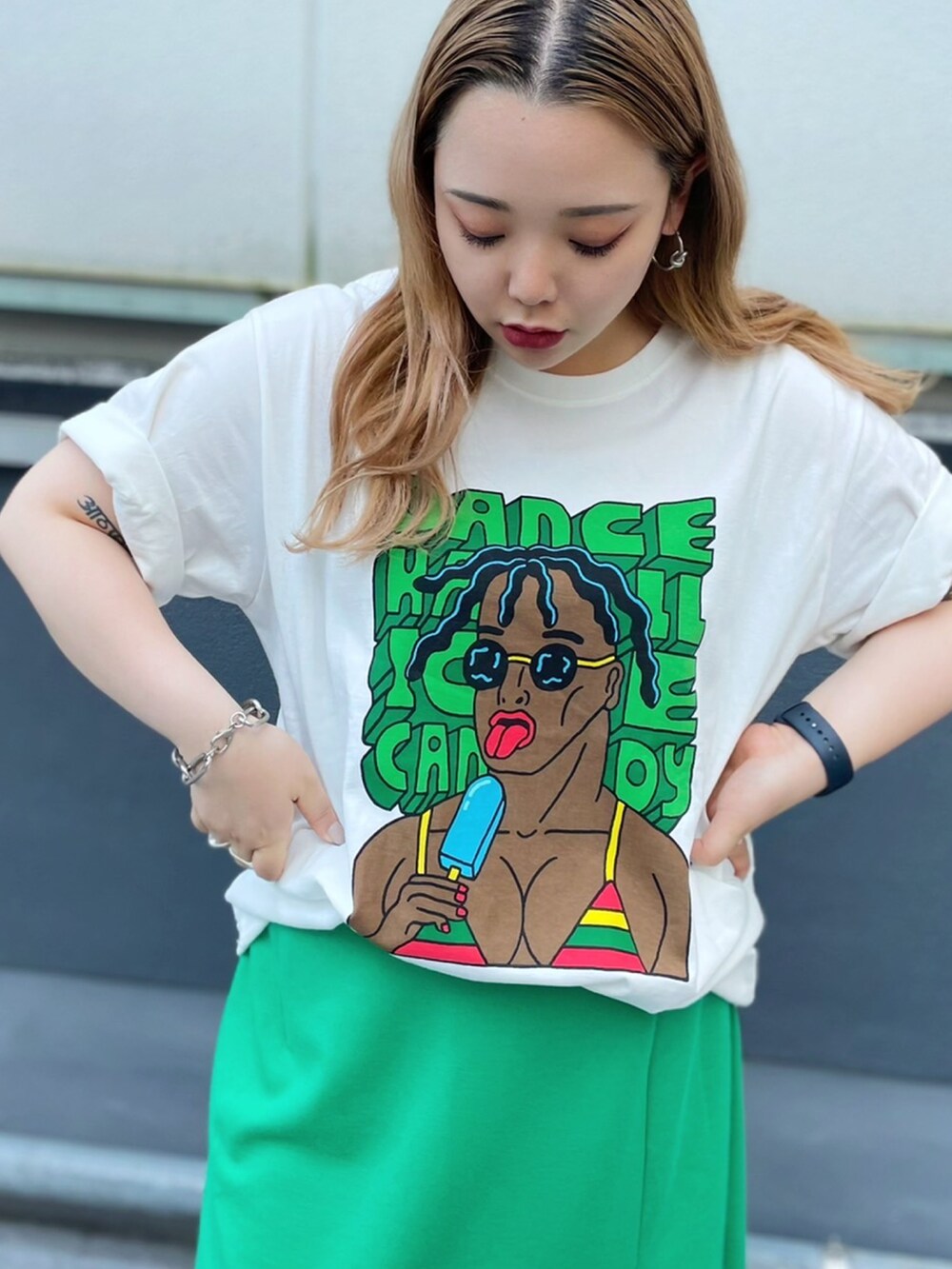 グリーン系のスカート、ホワイト系のTシャツ/カットソー、ブラック系のサンダルを着用したレディースの夏コーディネートの2枚目の写真