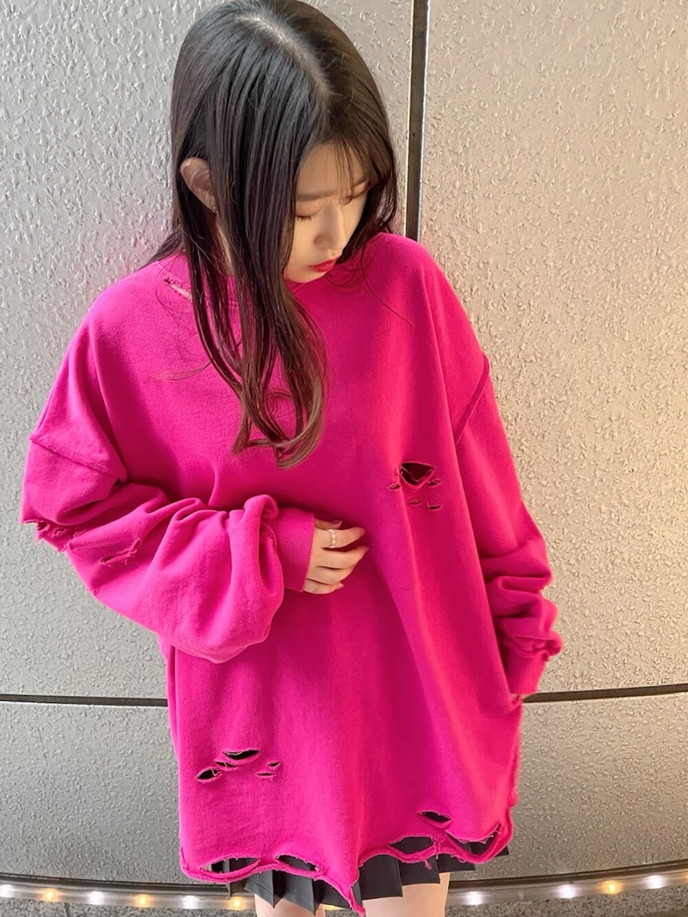 ピンク系のスウェット、ブラック系のスカート、ブラック系のブーツを着用したレディースの春コーディネートの2枚目の写真