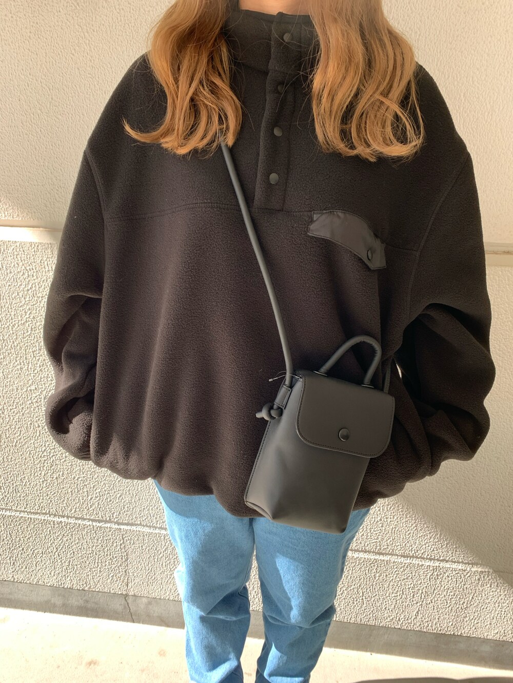 ブラック系のブルゾン、ブルー系のチノパンツ、ブラック系のスニーカーを着用したレディースの秋コーディネートの2枚目の写真