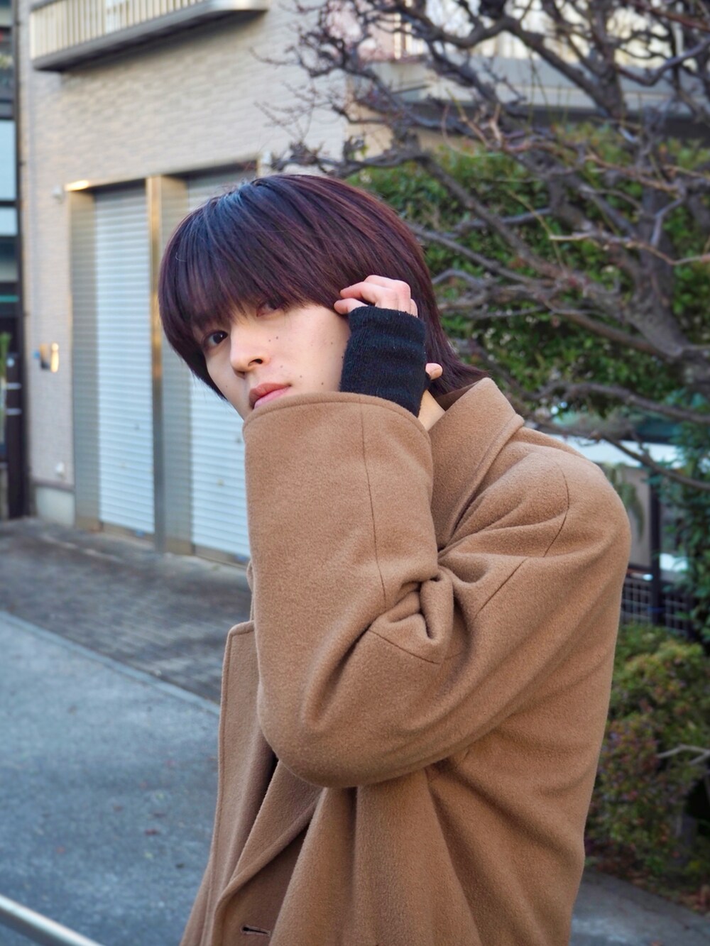 ブラック系のスニーカー、ブラック系のデニムパンツ、ベージュ系のチェスターコートを着用したメンズの冬コーディネートの2枚目の写真