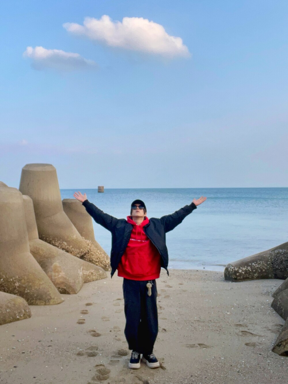 ブラック系のスニーカー、ブラック系のパンツ、レッド系のパーカーを着用したメンズの冬コーディネートの3枚目の写真