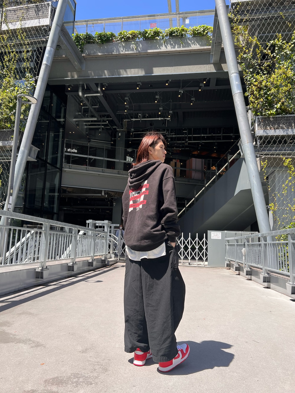 レッド系のスニーカー、ブラック系のパンツ、ブラック系のパーカーを着用したメンズの春コーディネートの2枚目の写真