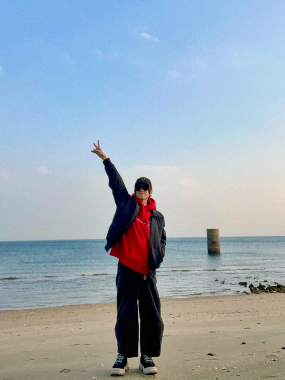 ブラック系のスニーカー、ブラック系のパンツ、レッド系のパーカーを着用したメンズの冬コーディネートの2枚目の写真