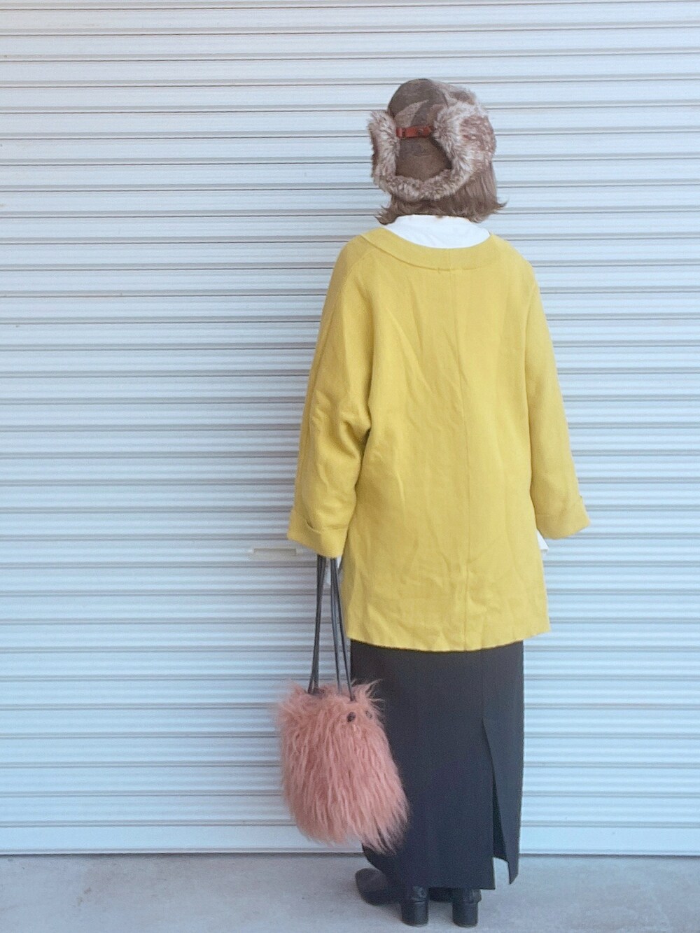 イエロー系のニット/セーター、ホワイト系のTシャツ/カットソー、ブラック系のスカートを着用したレディースの秋コーディネートの2枚目の写真