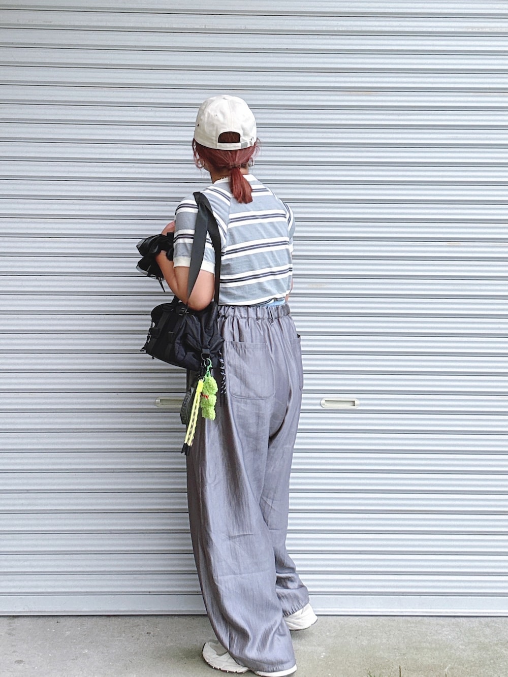 グレー系のトップス、グレー系のパンツ、ブラック系のバッグを着用したレディースの夏コーディネートの2枚目の写真