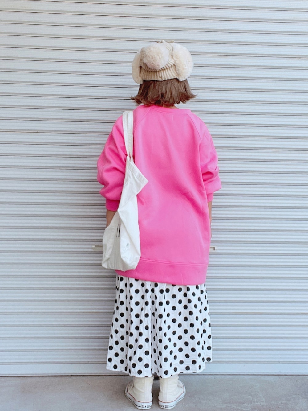 ピンク系のスウェット、ホワイト系のトートバッグ、ホワイト系のスカートを着用したレディースの秋コーディネートの2枚目の写真