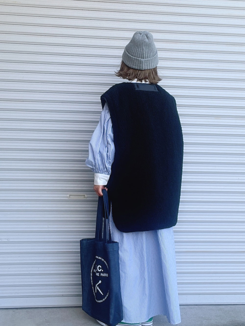 ブラック系のブルゾン、ブルー系のワンピース、ブルー系のトートバッグを着用したレディースの冬コーディネートの2枚目の写真