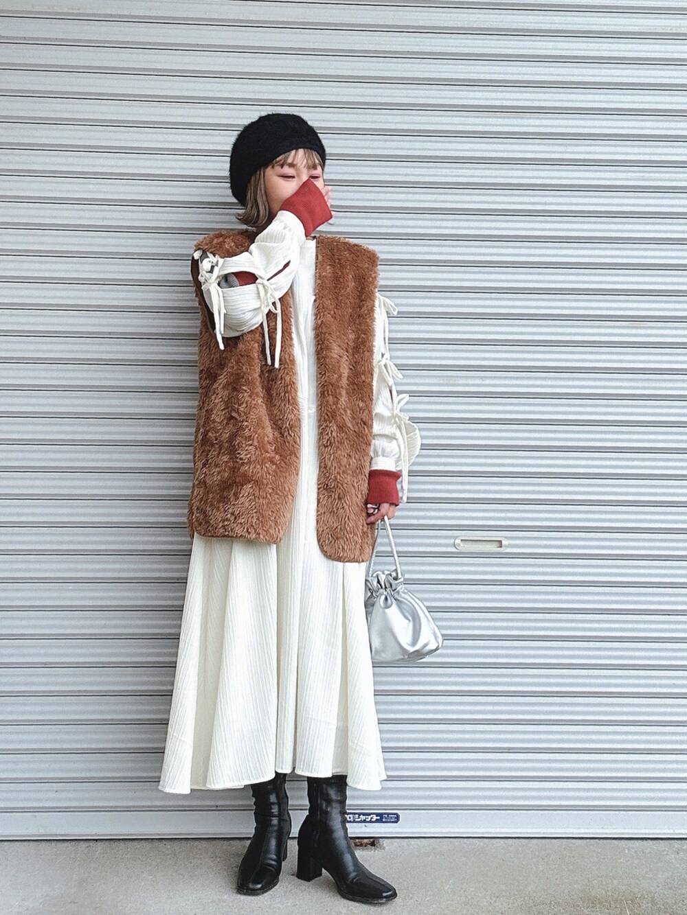 ブラウン系のベスト、ホワイト系のワンピース、グレー系のニット/セーターを着用したレディースの冬コーディネートの2枚目の写真