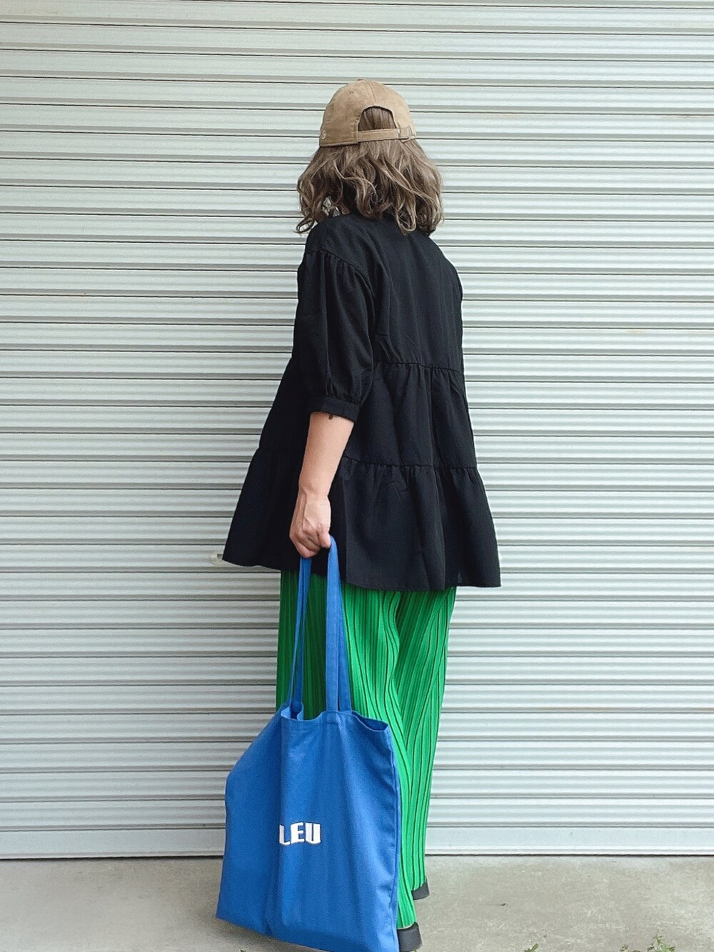 ブラック系のシャツ/ブラウス、グリーン系のその他パンツ、ブルー系のトートバッグを着用したレディースの春コーディネートの2枚目の写真