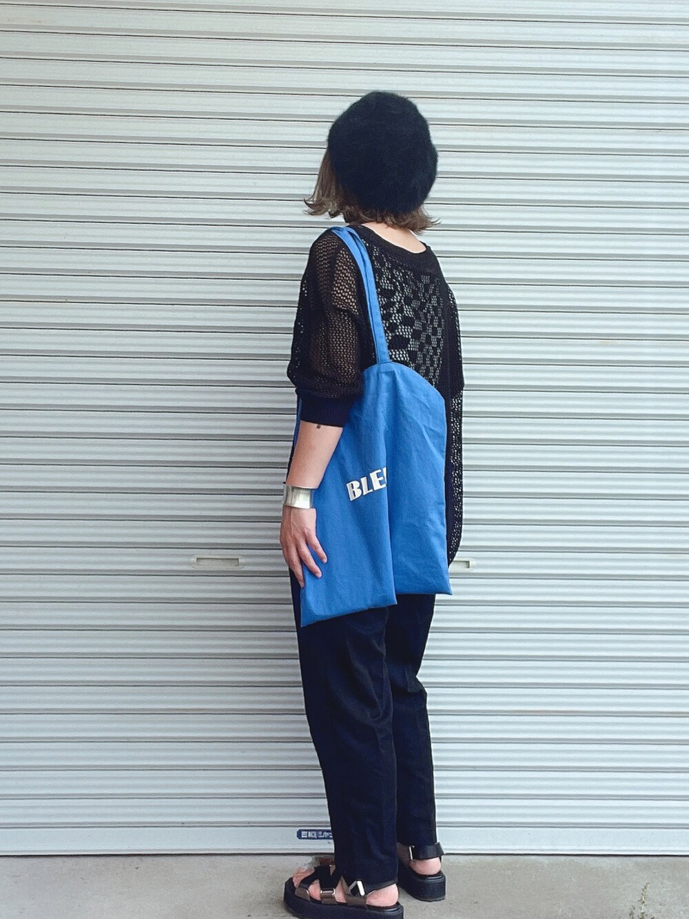 ブラック系のニット/セーター、ブラック系のタンクトップ、ブラック系のスラックスを着用したレディースの春コーディネートの2枚目の写真