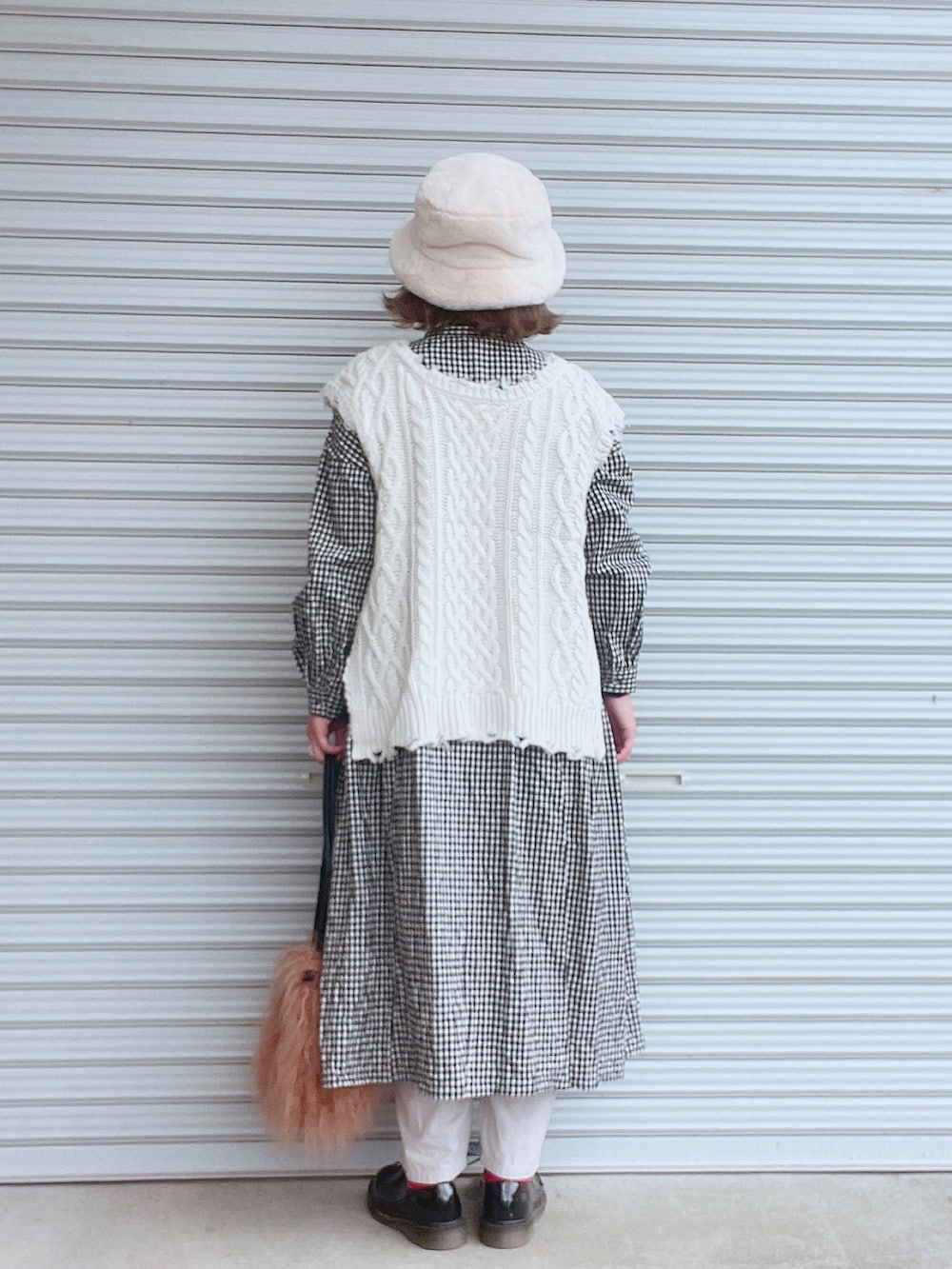 ブラック系のワンピース、ホワイト系のベスト、ブラウン系のショルダーバッグを着用したレディースの冬コーディネートの2枚目の写真