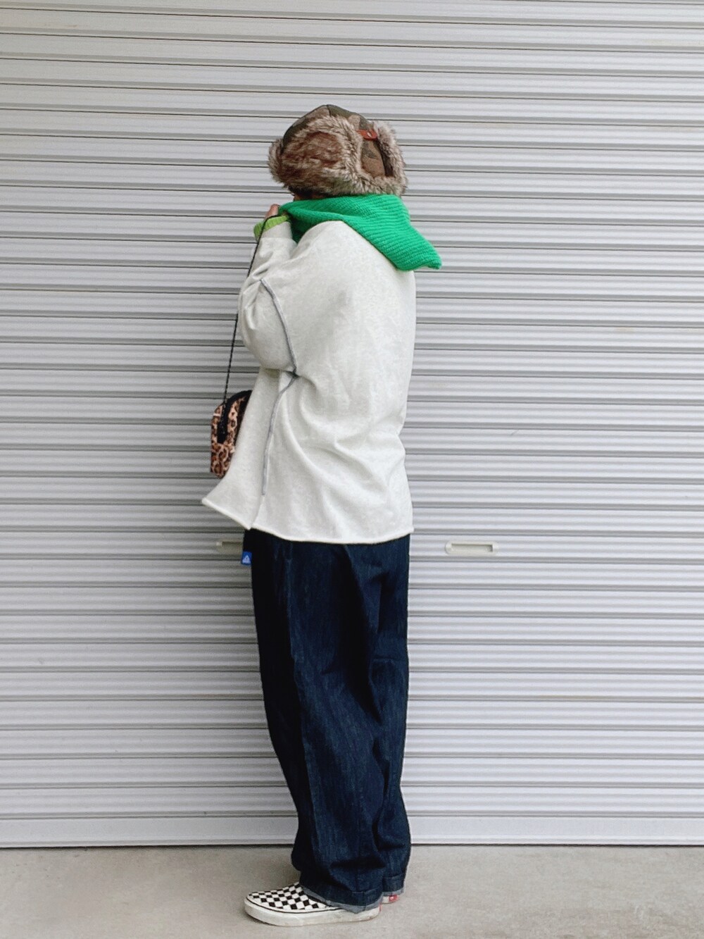 グレー系のスウェット、グリーン系のニット/セーター、ブルー系のデニムパンツを着用したレディースの冬コーディネートの2枚目の写真