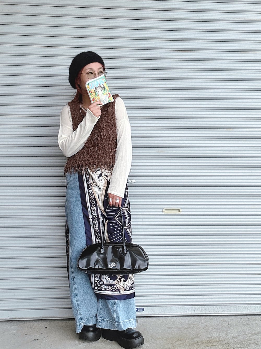 ブルー系のデニムパンツ、ブラウン系のベスト、ホワイト系のニット/セーターを着用したレディースの秋コーディネートの2枚目の写真