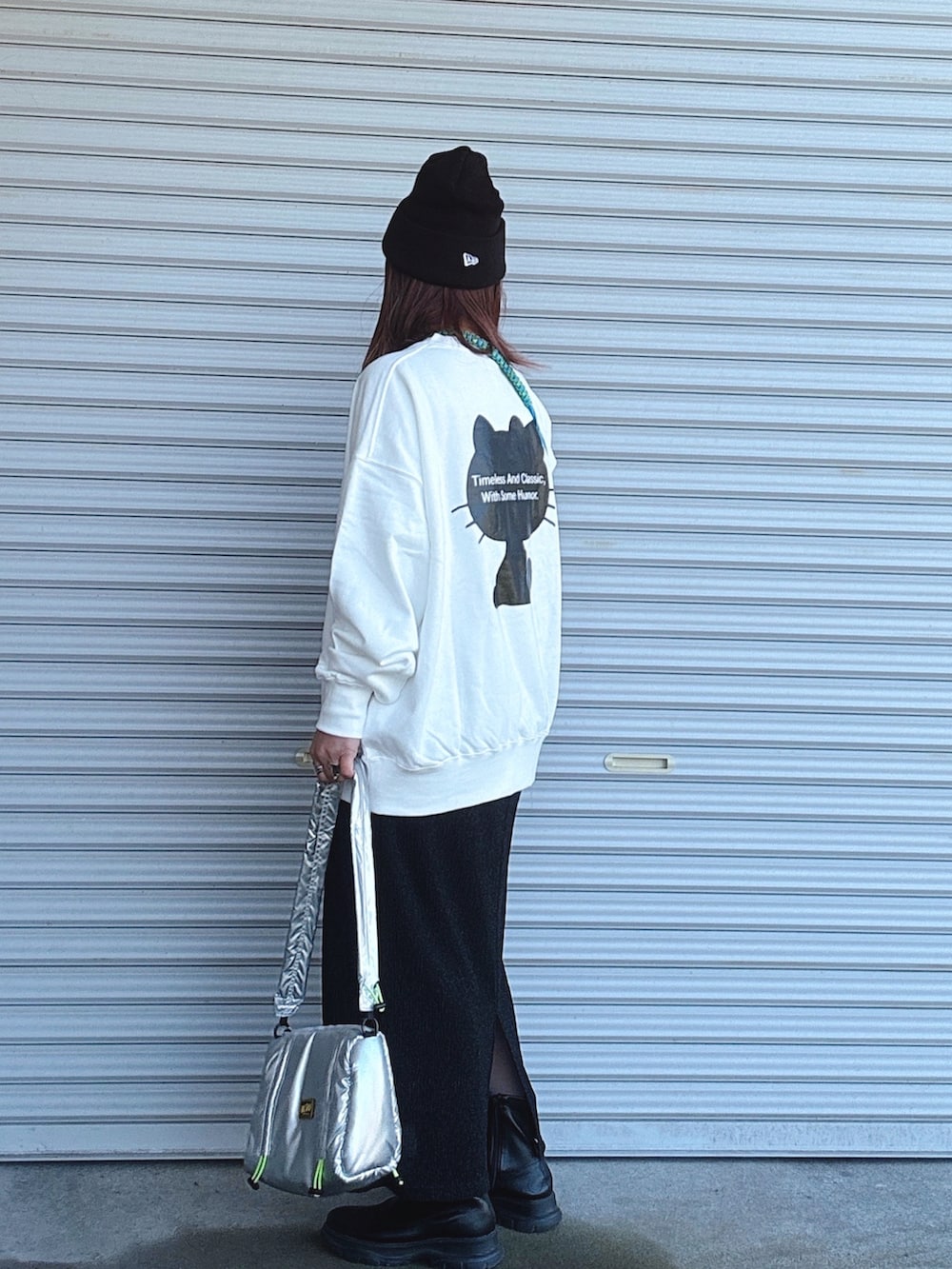 ブラック系のブーツ、シルバー系のショルダーバッグ、ブラック系のスカートを着用したレディースの冬コーディネートの2枚目の写真