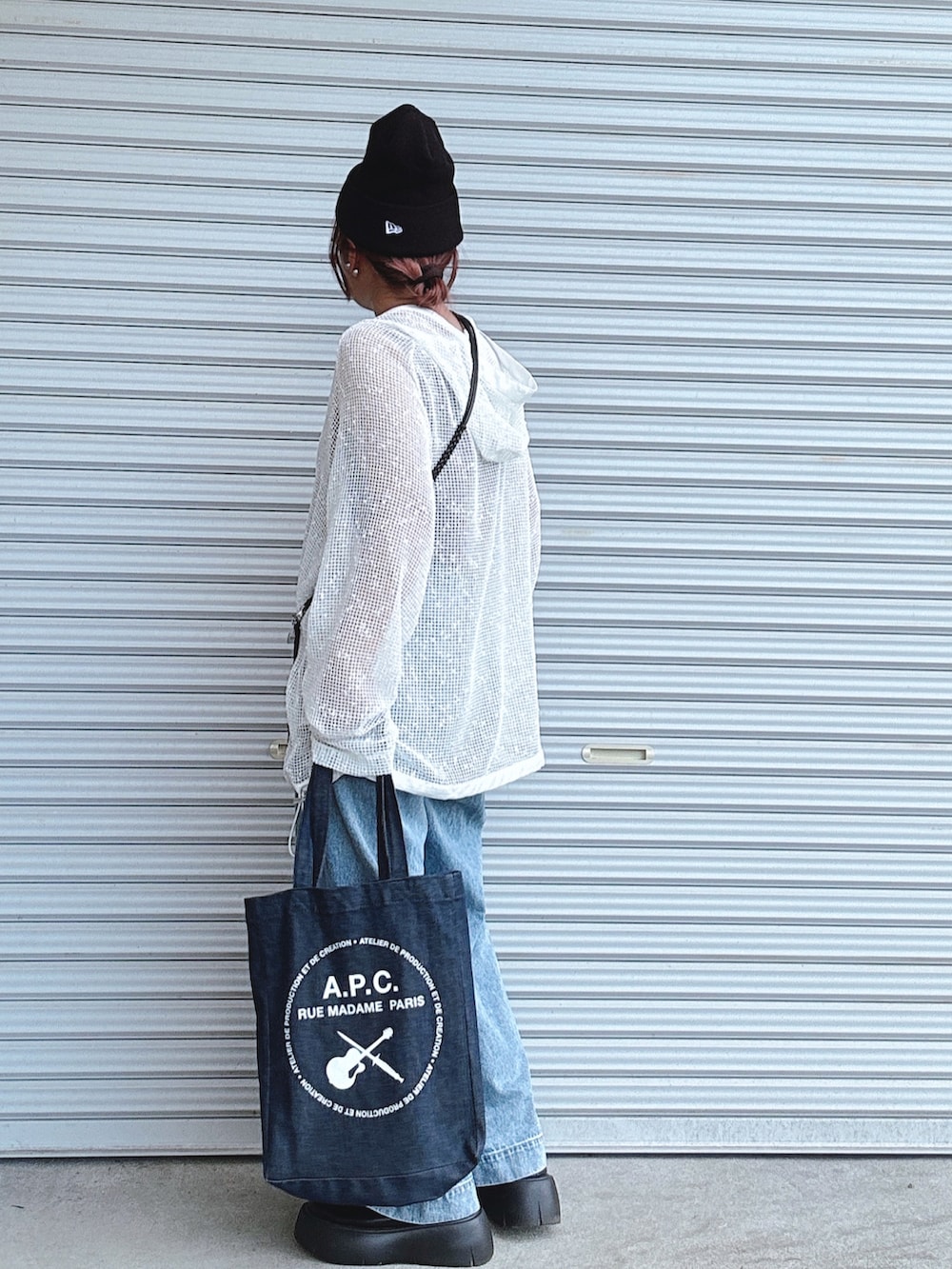 ホワイト系のパーカー、ブルー系のデニムパンツ、ブラウン系のタンクトップを着用したレディースの秋コーディネートの2枚目の写真