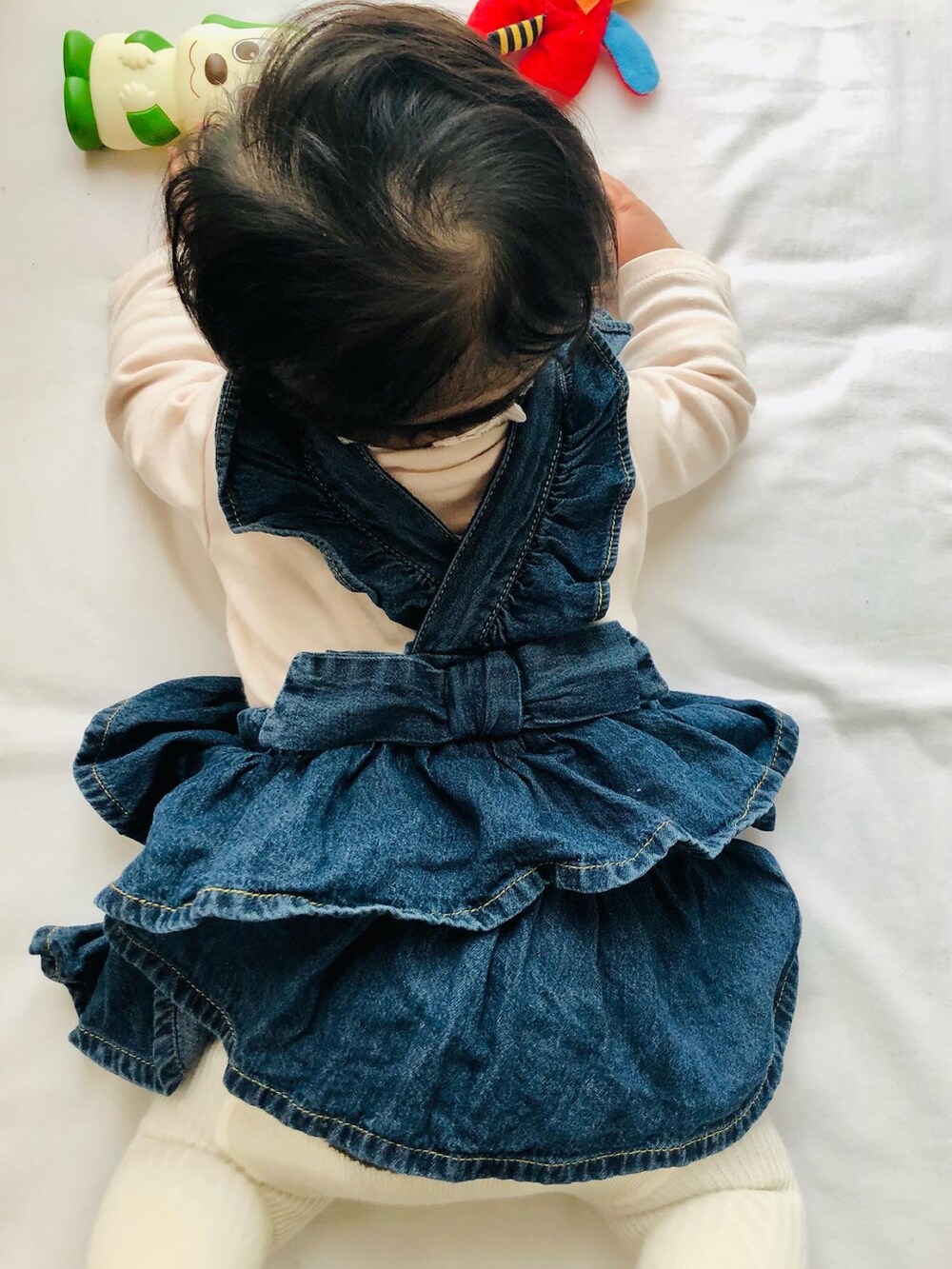 ピンク系のロンパース、ブルー系のその他ベビーウェア、ホワイト系のタイツ/ストッキングを着用したキッズの冬コーディネートの2枚目の写真