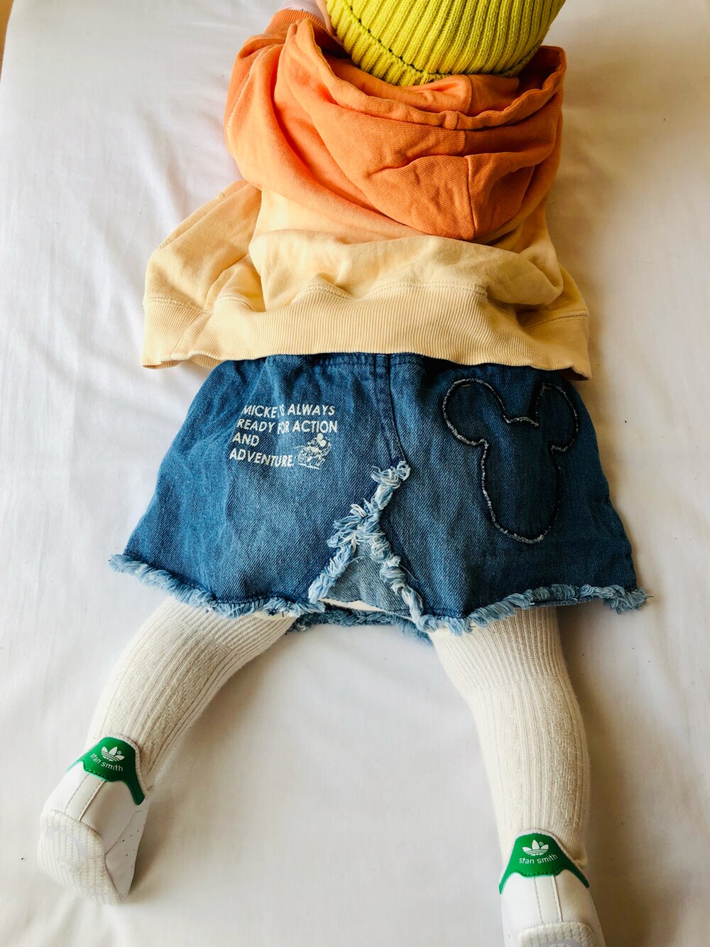 オレンジ系のパーカー、ブルー系のスカート、ホワイト系のスニーカーを着用したキッズの春コーディネートの3枚目の写真