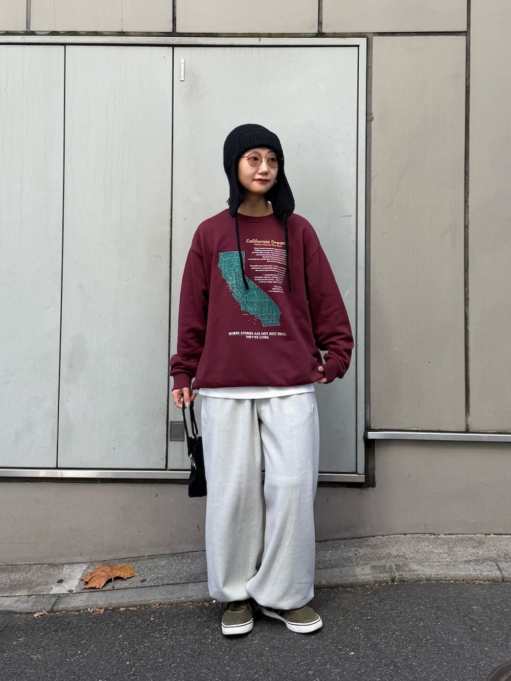 レッド系のスウェット、ブラック系のショルダーバッグ、グレー系のスウェットパンツを着用したレディースの秋コーディネートの3枚目の写真