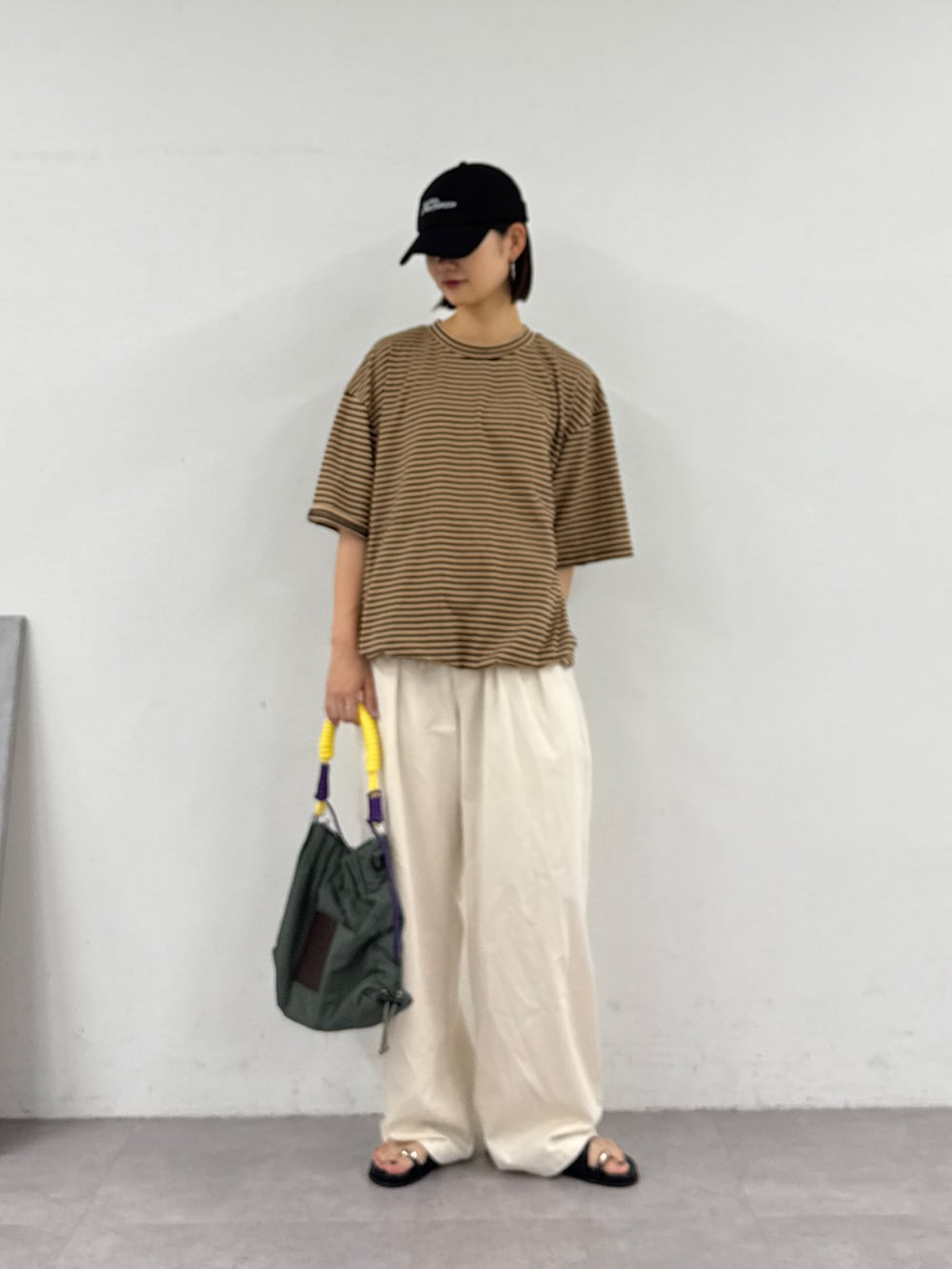 ベージュ系のTシャツ/カットソー、ホワイト系のデニムパンツ、グリーン系のトートバッグを着用したレディースの夏コーディネートの2枚目の写真