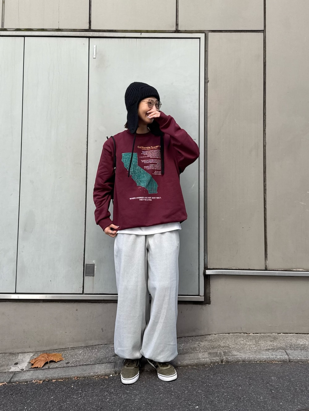 レッド系のスウェット、ブラック系のショルダーバッグ、グレー系のスウェットパンツを着用したレディースの秋コーディネートの2枚目の写真