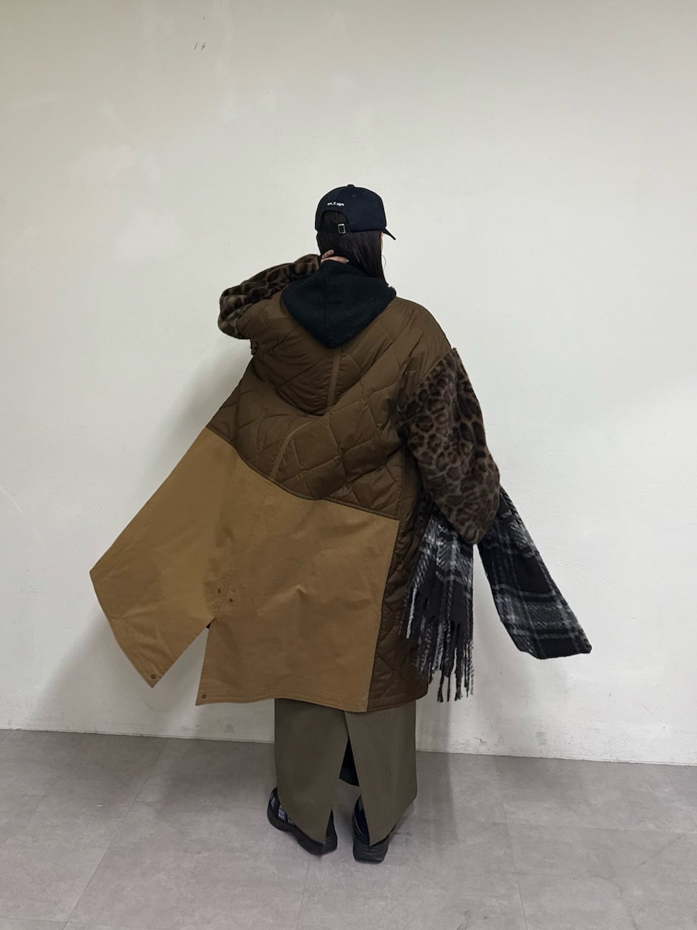 ブラウン系のノーカラーコート、グリーン系のスカート、ブラック系のパーカーを着用したレディースの秋コーディネートの3枚目の写真