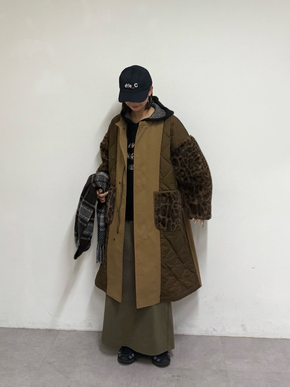 ブラウン系のノーカラーコート、グリーン系のスカート、ブラック系のパーカーを着用したレディースの秋コーディネートの4枚目の写真