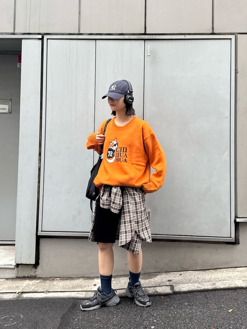 オレンジ系のニット/セーター、ブラック系のトートバッグ、ブラウン系のシャツ/ブラウスを着用したレディースの秋コーディネートの2枚目の写真