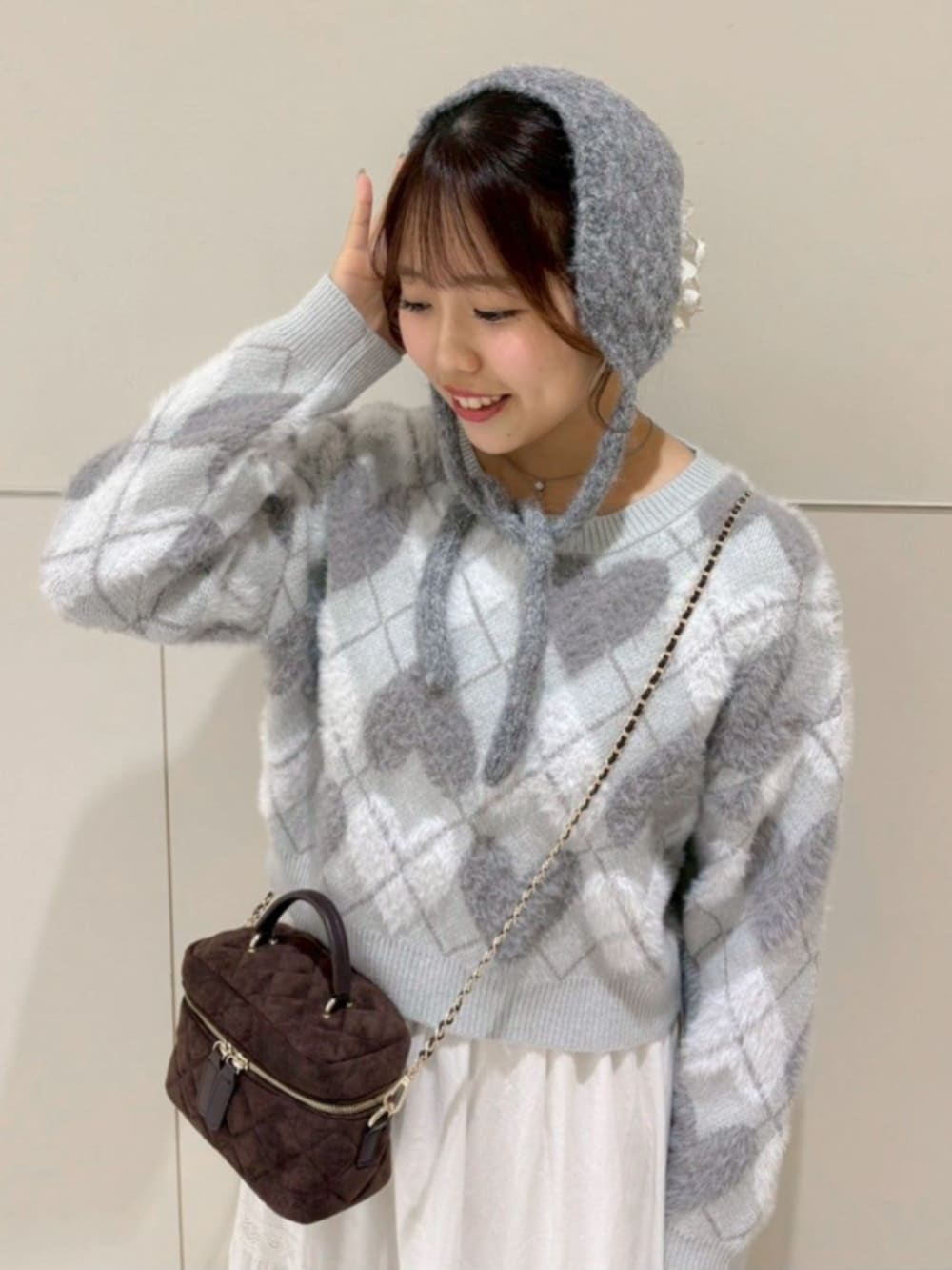 ホワイト系のスカート、グレー系のニット/セーター、ブラウン系のショルダーバッグを着用したレディースの秋コーディネートの2枚目の写真