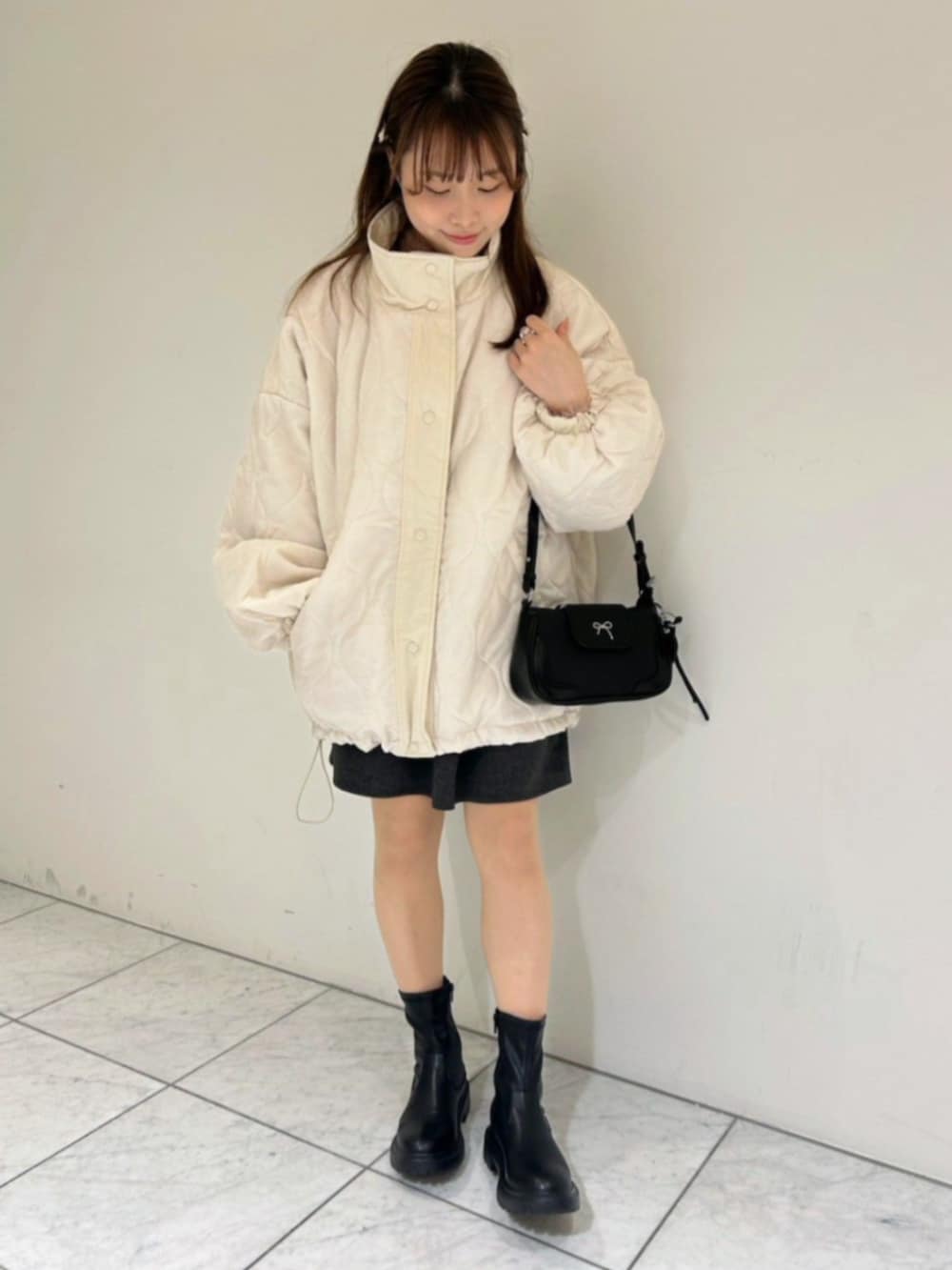ホワイト系のナイロンジャケット、グレー系のスカート、ピンク系のニット/セーターを着用したレディースの秋コーディネートの4枚目の写真