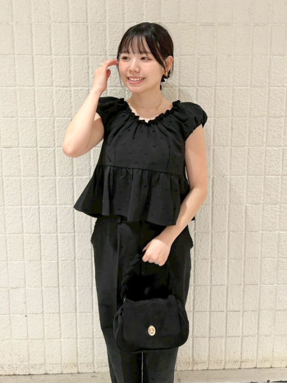 ブラック系のショルダーバッグ、ブラック系のキャミソール、ブラック系のパンツを着用したレディースの秋コーディネートの2枚目の写真