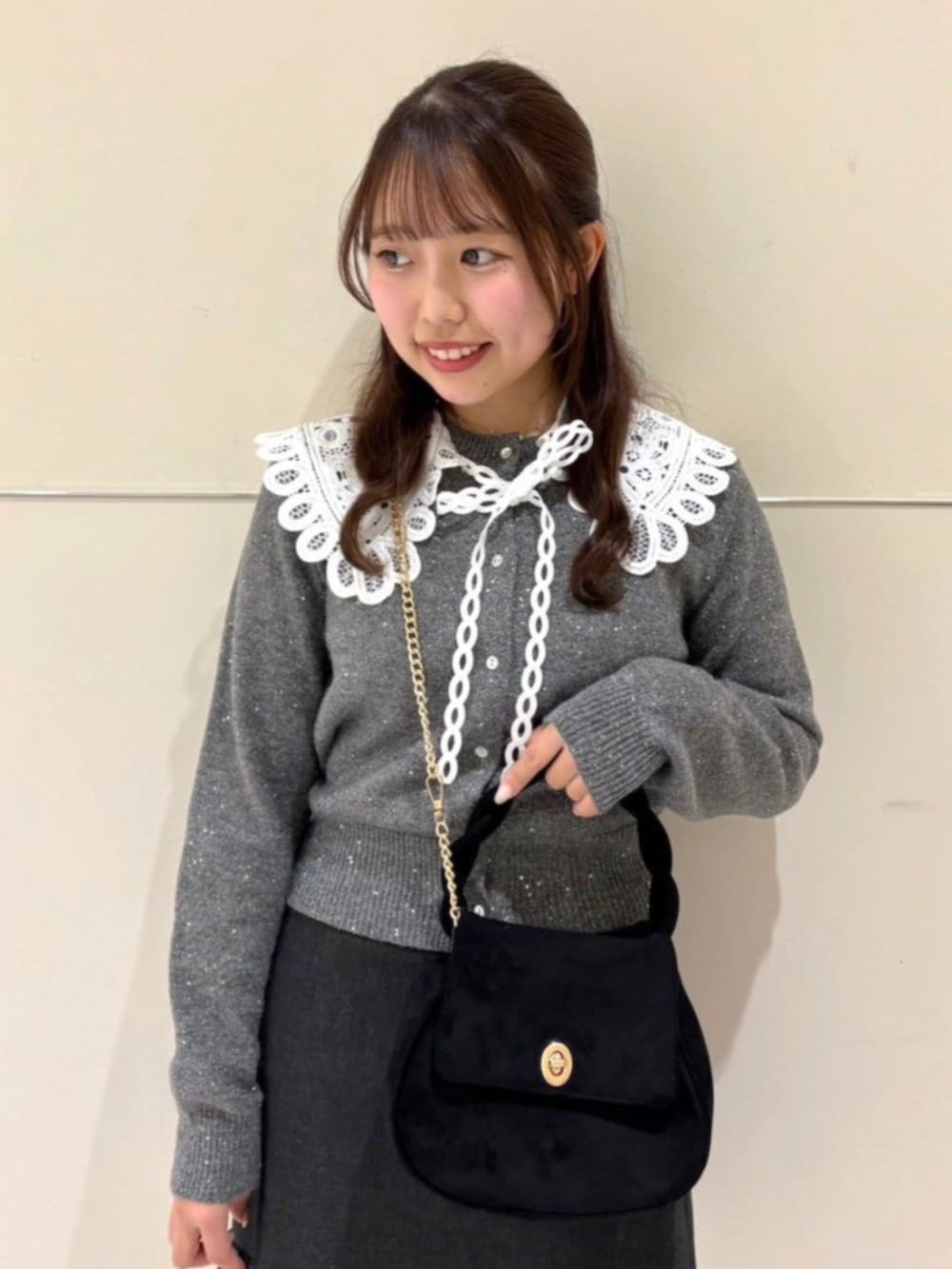 ブラック系のショルダーバッグ、グレー系のニット/セーター、グレー系のスカートを着用したレディースの冬コーディネートの2枚目の写真