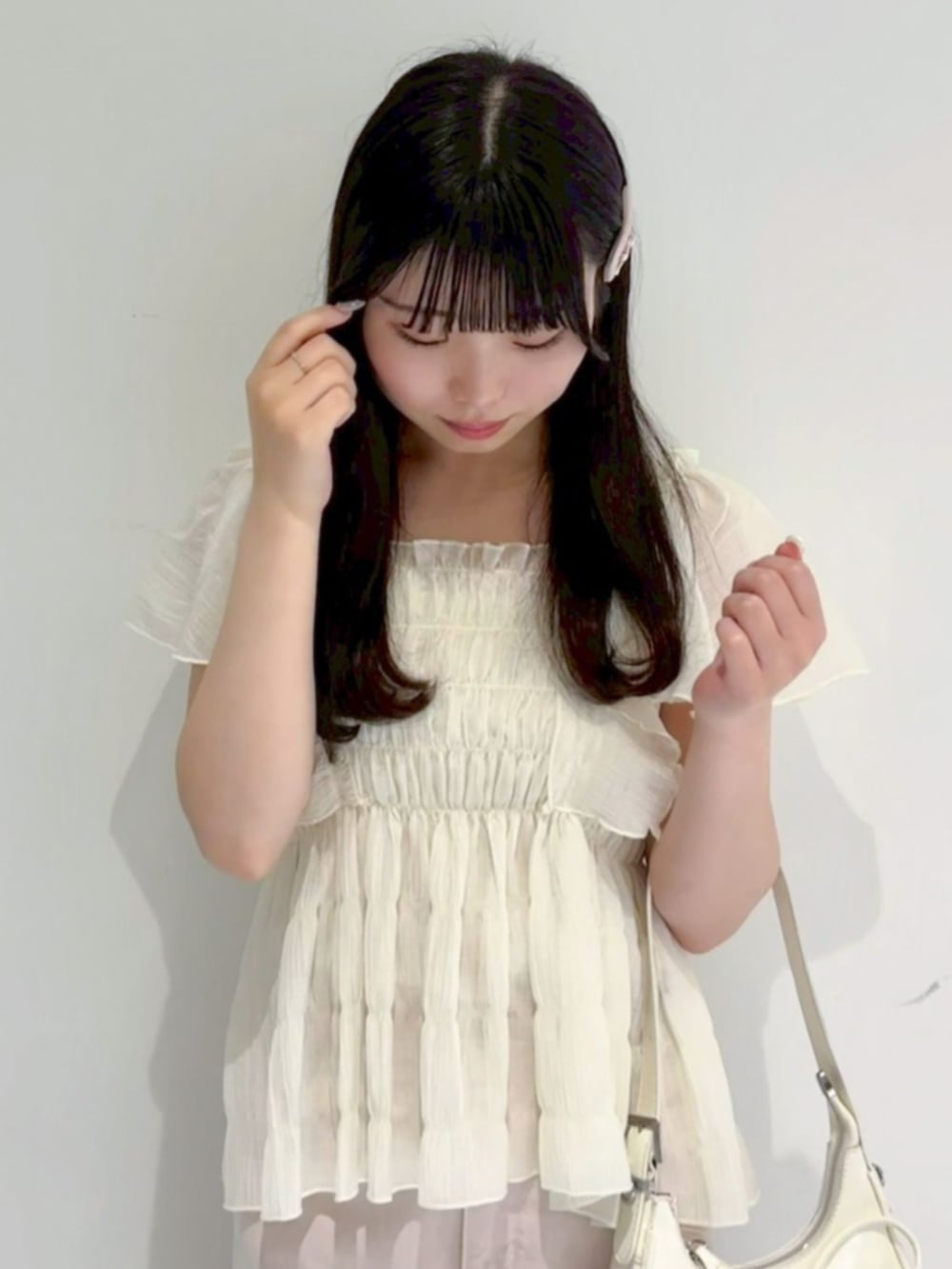 ピンク系のデニムパンツ、ホワイト系のシャツ/ブラウス、ホワイト系のショルダーバッグを着用したレディースの夏コーディネートの2枚目の写真
