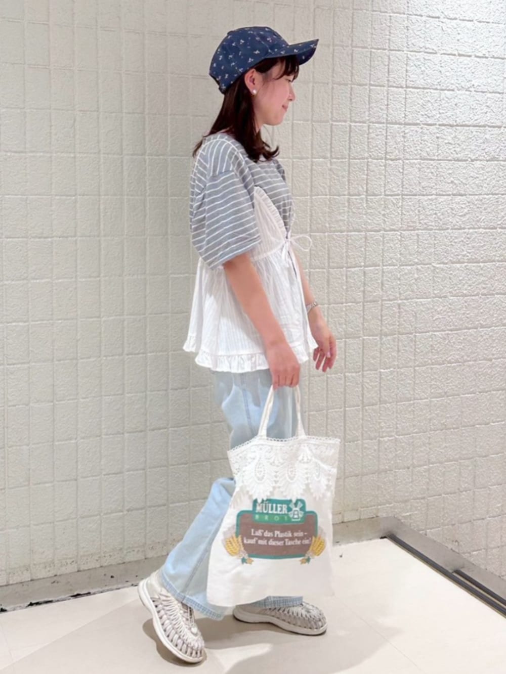 ブルー系のデニムパンツ、ホワイト系のキャミソール、ブルー系のキャップを着用したレディースの夏コーディネートの2枚目の写真