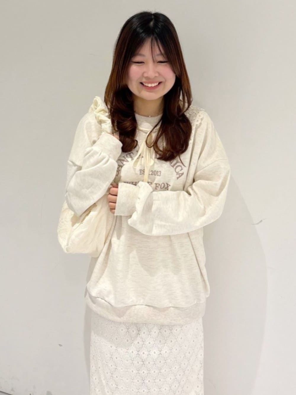 ホワイト系のショルダーバッグ、ホワイト系のスウェット、ホワイト系のスカートを着用したレディースの春コーディネートの2枚目の写真