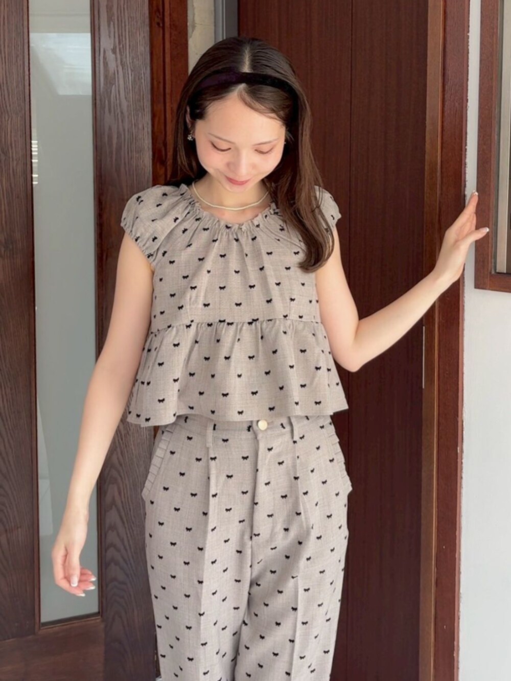 ホワイト系のニット/セーター、ブラウン系のトップス、ブラウン系のパンツを着用したレディースの夏コーディネートの2枚目の写真