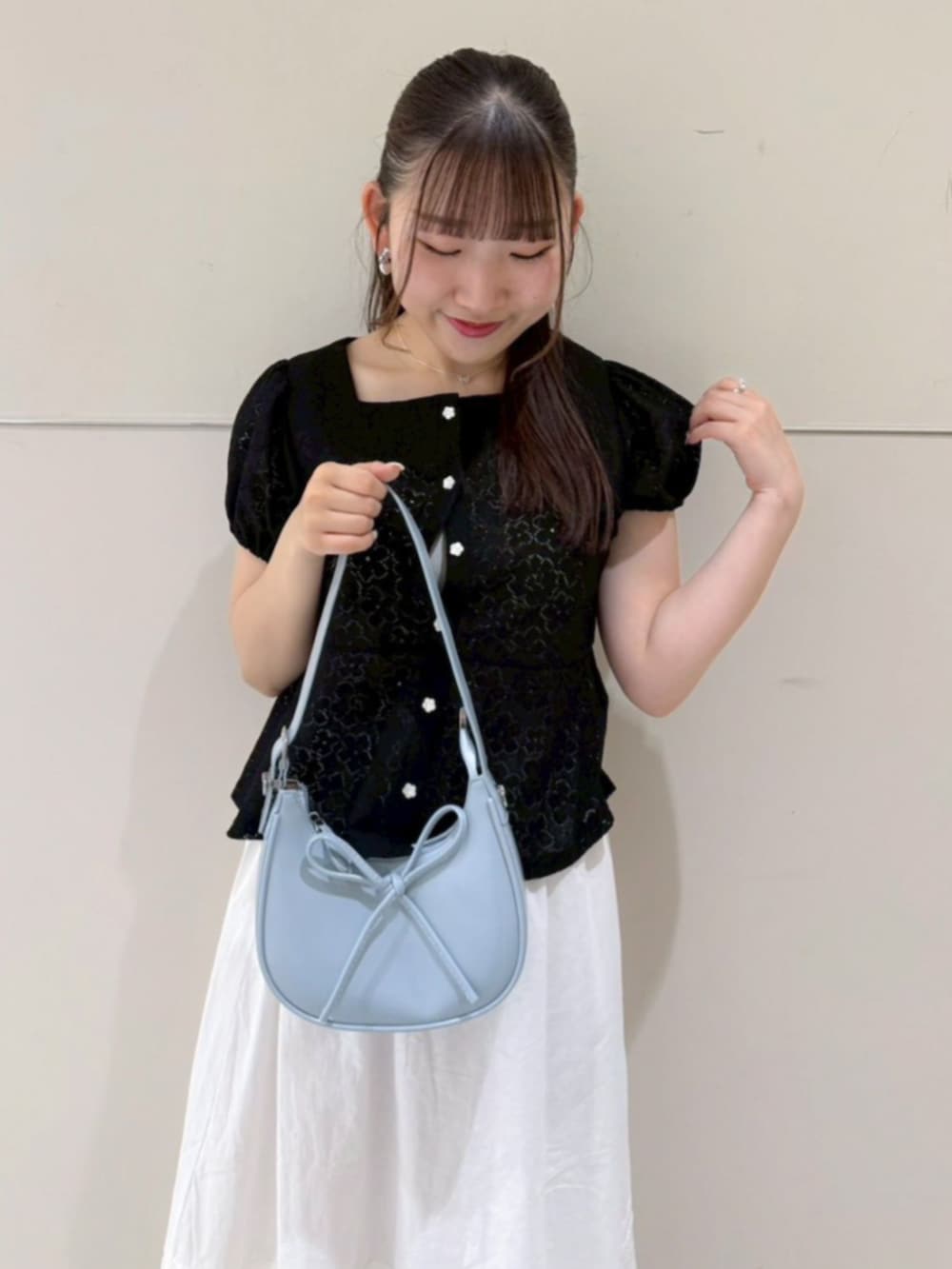 ホワイト系のスカート、ブラック系のシャツ/ブラウス、ブルー系のショルダーバッグを着用したレディースの春コーディネートの2枚目の写真