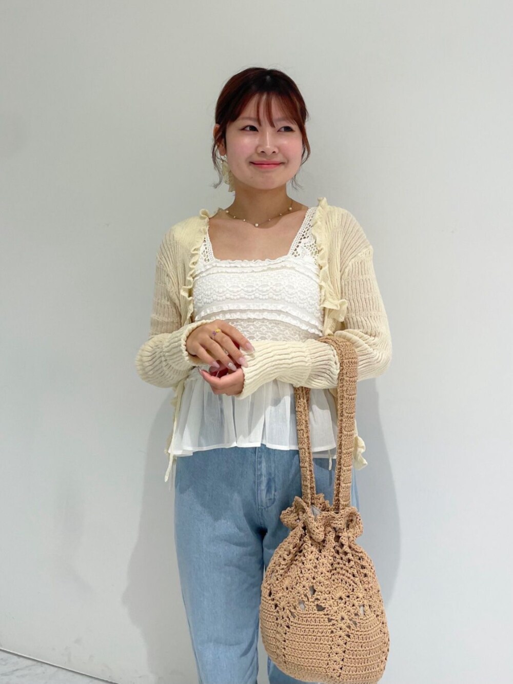 ブルー系のデニムパンツ、ホワイト系のカーディガン/ボレロ、ホワイト系のキャミソールを着用したレディースの夏コーディネートの2枚目の写真