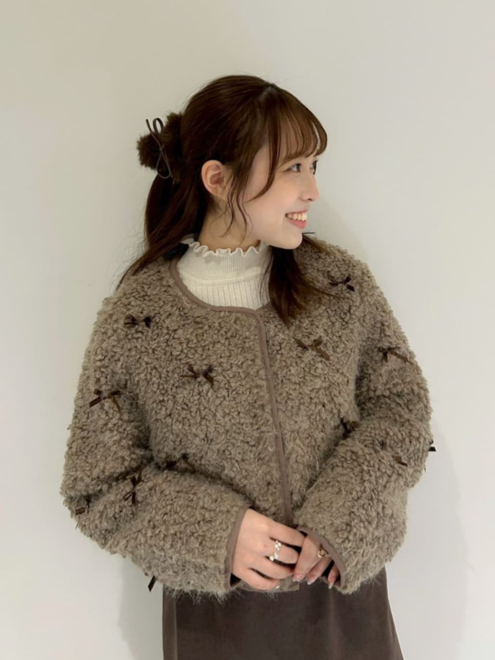 ホワイト系のニット/セーター、ブラウン系のノーカラージャケット、ブラウン系のスカートを着用したレディースの秋コーディネートの2枚目の写真