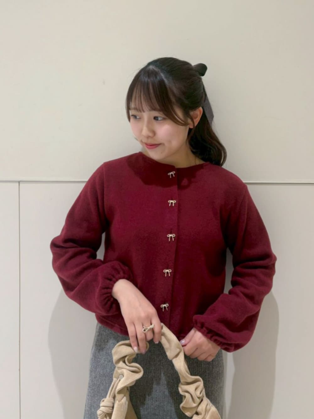 ベージュ系のショルダーバッグ、レッド系のカーディガン/ボレロ、グレー系のスカートを着用したレディースの秋コーディネートの2枚目の写真