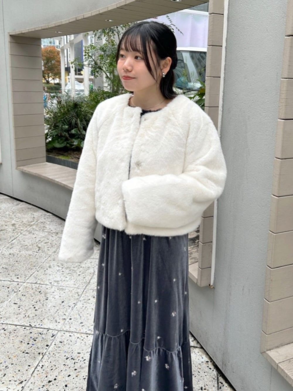 ホワイト系のノーカラーコート、グレー系のワンピース、ブルー系のニット/セーターを着用したレディースの冬コーディネートの2枚目の写真