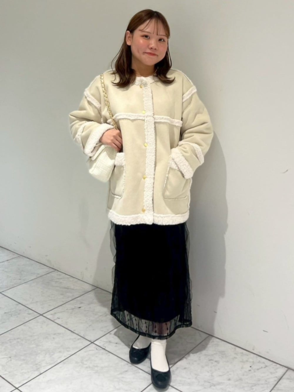 ホワイト系のショルダーバッグ、ブラック系のスカート、ホワイト系のムートンコートを着用したレディースの秋コーディネートの3枚目の写真