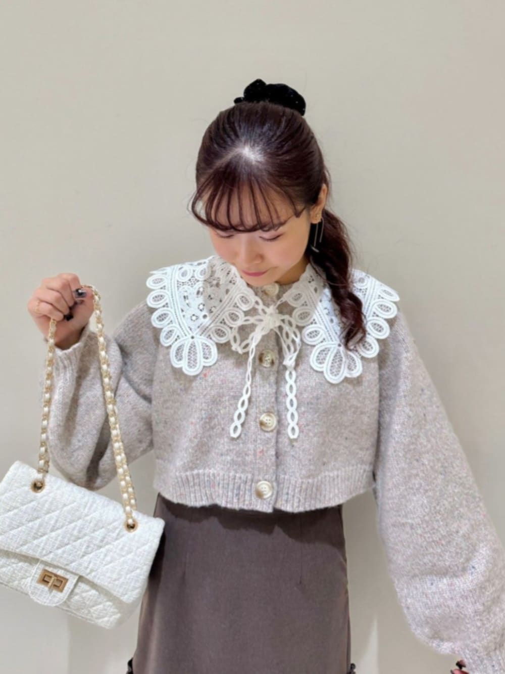 ホワイト系のショルダーバッグ、ブラウン系のスカート、ベージュ系のカーディガン/ボレロを着用したレディースの秋コーディネートの2枚目の写真