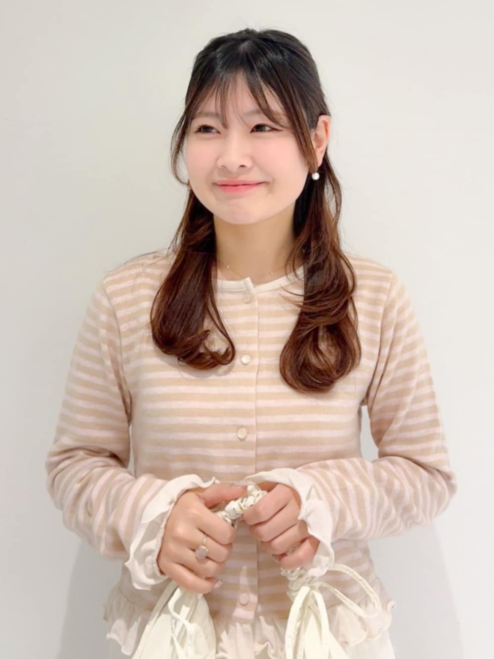 ホワイト系のショルダーバッグ、ホワイト系のスカート、ベージュ系のカーディガン/ボレロを着用したレディースの春コーディネートの2枚目の写真