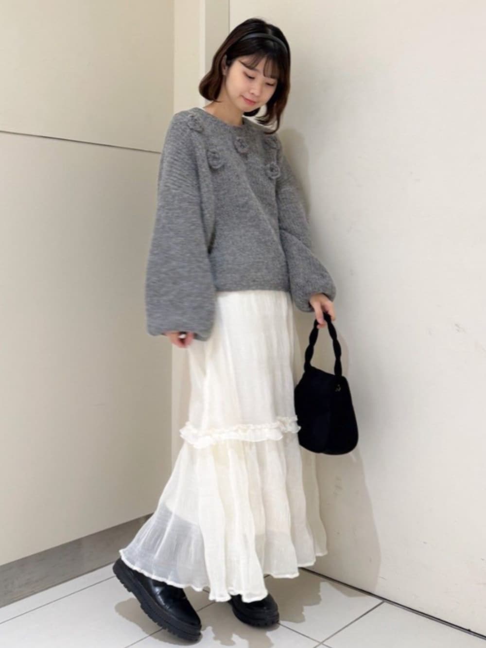 ブラック系のショルダーバッグ、グレー系のニット/セーター、ホワイト系のスカートを着用したレディースの冬コーディネートの3枚目の写真